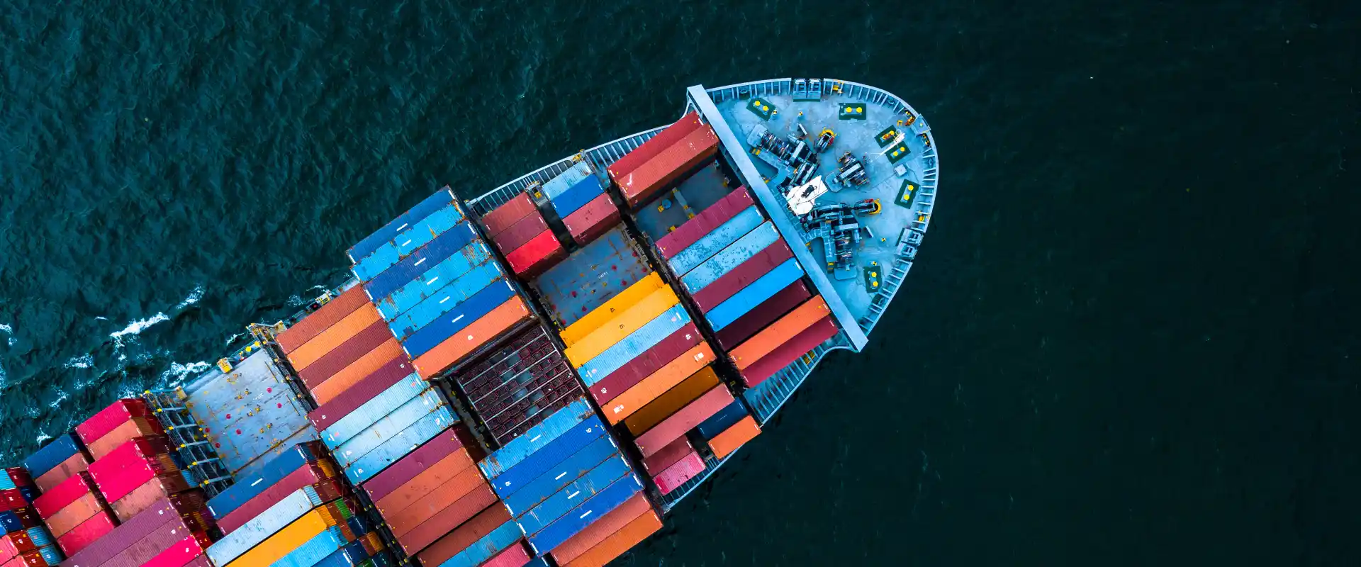 Luftaufnahme: Containerschiff mit bunten Frachtcontainern auf See